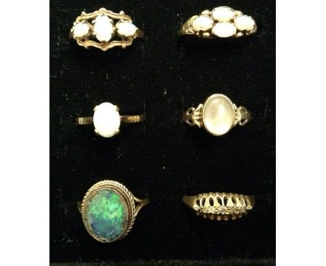 Rings - a graduated five stone diamond ring, size M;  a white opal oval doublet dress ring, size k;  a similar four stone;  o