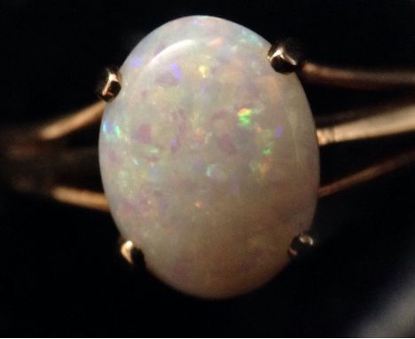 An opal solitaire ring, single pale cream oval opal, playing tones of green, blue and orange, 9ct gold shank, size M, 2.4g gr