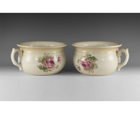 Early 20th century AD. A matched pair of cream-glaze ceramic chamber pots, each with flared rim, scrolled handle, floral tran