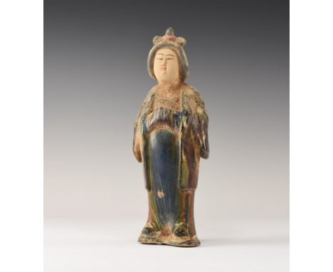 An undated archaistic glazed ceramic figurine of a courtly lady standing with hands in the folds of her sleeved; hollow to th