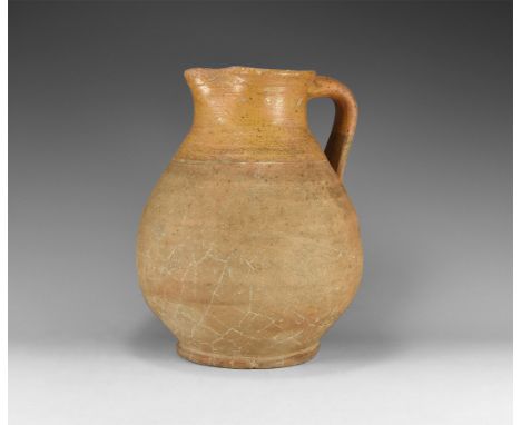 17th century AD. A bulbous ceramic ewer with discoid base, flared rim with pouring lip, strap handle to the rear, circumferen