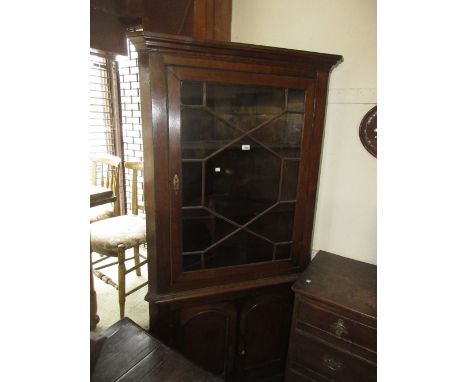 George III oak standing corner cabinet with a moulded cornice above an astragal glazed door with twin panel door below, raise