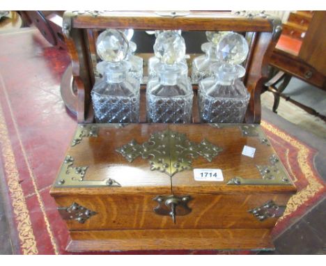 Edwardian oak and silver plate mounted three bottle tantalus fitted with three hobnail cut bottles, a concealed drawer to the