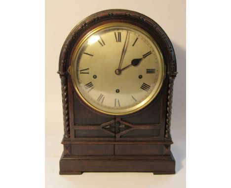 A late 19th/early 20th Century carved oak bracket clock of arched form with twisted supports, silvered convex Roman dial, thr