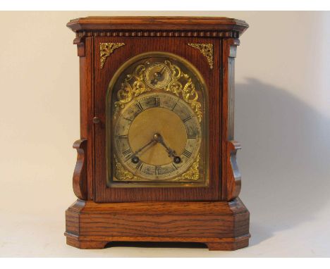 An early 20th Century oak bracket clock, the brass dial plate with gilt centre and spandrels, silvered Roman chapter ring wit