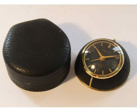 GUBELIN: a gilt metal and leather 8 day travelling alarm clock with black dial and date aperture, no. 21069, base diameter 16