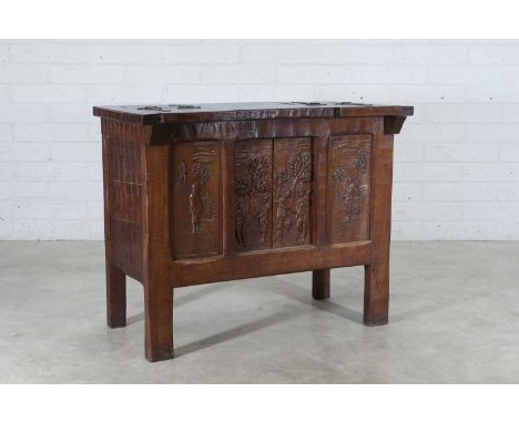 An Arts and Crafts oak chest, 1920s, the top with sliding and hinged compartments, the front carved with gentlemen with shotg