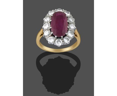 A Ruby and Diamond Cluster Ring, the central oval cut ruby within a border of round brilliant cut diamonds in white claw sett