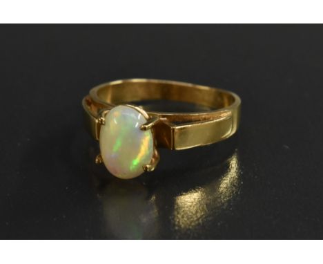 An opal solitaire ring, oval opal cabochon flashing  violet, green, red and orange play, four claw set upon an open shoulder 