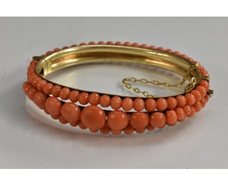 A coral bead encrusted hinge bangle, central row of graduated pink coral beads largest approx 8.5mm diameter, flanked either 