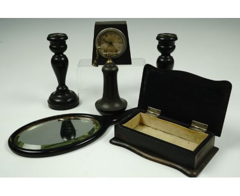 A late 19th / early 20th Century ebony dressing table set including a pair of candlesticks (15 cm), and a boudoir clock