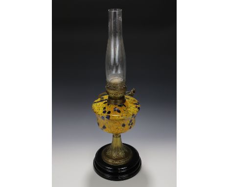 A late 19th / early 20th Century oil lamp, having a marbled glass reservoir supported on a brass trumpet-form column and blac