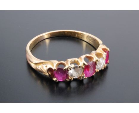 A ruby and diamond ring, comprising a central oval ruby of 4 mm x 3 mm, flanked by two round cut rubies divided by two brilli