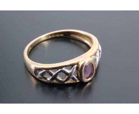 An amethyst and two colour 9 ct gold ring, the oval amethyst bezel-set between the interlace-filled bifurcated shoulders of t