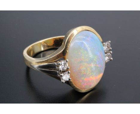 An impressive opal and diamond dress ring, comprising an oval opal cabochon of 16 mm x 12 mm, bezel set between the bifurcate