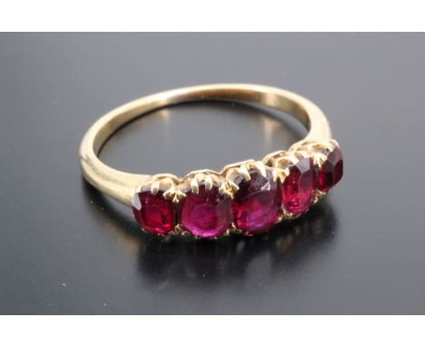 A five stone ruby ring, comprising graded oval stones claw set on a yellow metal shank, largest stone 5 mm x 4 mm, Q, 2.9 g