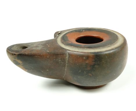 A Roman redware lamp of unadorned compressed round form with a discus shaped top and large filling hole and a beak shaped spo