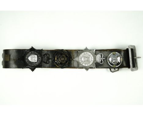 A leather police belt mounted with Doncaster Police insignia, comprising day and night helmet plates and ball top, cap badges