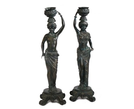 A pair of Italian bronzed Blackamoor candlestick figures, formed as a man and a woman holding a jardiniere above their heads,
