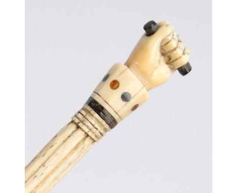 A George III whalebone and inlaid walking stick, the handle in the form of a clenched fist holding a baton above a reeded col