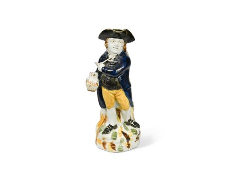 standing, holding a pipe and jug of ale on a rocky base, painted in blue, orange and brown, 29cm highProvenance:Arthur Henry 
