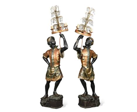 theatrically dressed and holding six light candelabra with cut glass lustres, on raised rocky bases,220cm highProvenance: Jul
