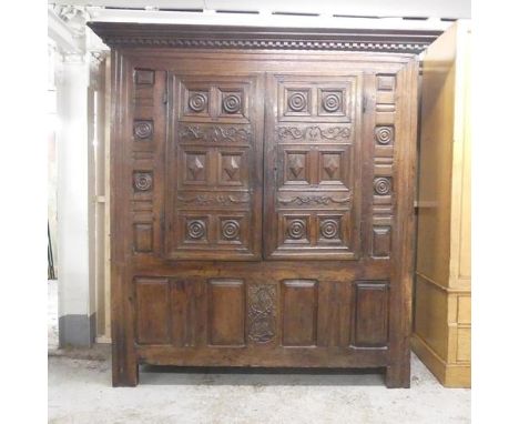 A 17th century and later panelled oak larder cupboard, with two doors revealing a shelf fitted interior with lifting lid cove