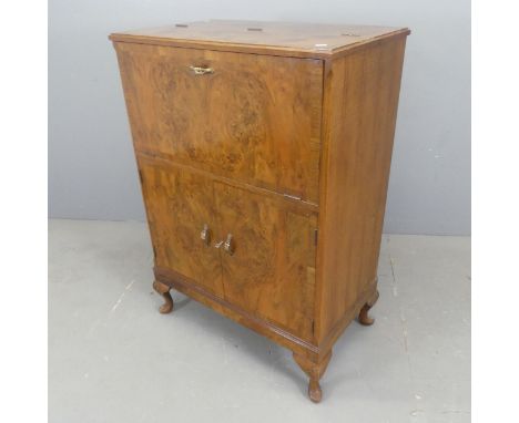 A mid-century Art Deco style walnut veneered cocktail cabinet, the fall front revealing a fitted mirrored interior with cupbo