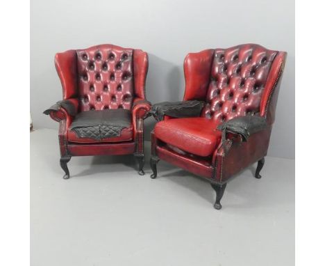 A pair of modern red button-back and studded leather upholstered Chesterfield style wingback fireside armchairs, patched with