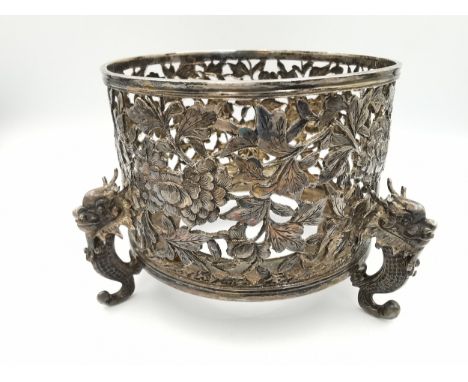 An early 20th century Chinese carved and pierced silver bottle coaster by Wang Hing, decorated with peonies with intricate en