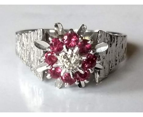 A diamond and ruby cluster ring on an 18ct white gold setting: the round brilliant-cut diamond 2.2mm, illusion set, surrounde