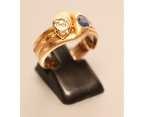 A GENTLEMAN'S DRESS RING as two entwined snakes, the heads set with an old mine cut diamond and an oval facet cut sapphire, a