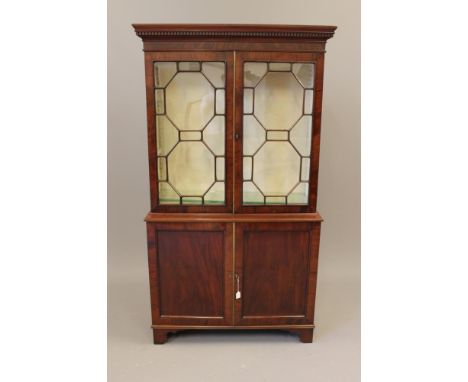 A MAHOGANY BOOKCASE, 18th century and later, the dentil moulded cornice over two astragal glazed doors enclosing a silk lined