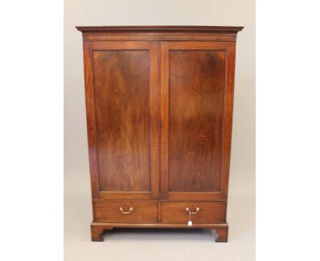 A MAHOGANY WARDROBE, part 18th century, the dentil moulded cavetto cornice over two panelled doors enclosing a hanging space,