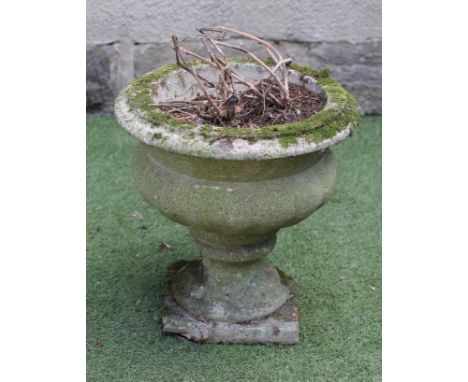 A SANDSTONE TROUGH of rough hewn circular form, 18" x 13", together with a composition stone urn with moulded rim, lobed body