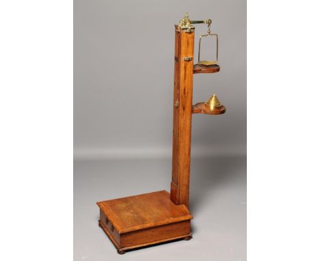 AN OAK STANDING HEIGHT AND WEIGHT JOCKEY SCALES, c.1900, with brass mounts and weights, the square shaft with sliding rule an