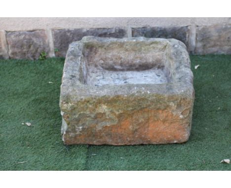 A SANDSTONE TROUGH of rough hewn irregular square form, 23" (approx.) x 21 1/2" x 12 1/2" (Est. plus 21% premium inc. VAT)