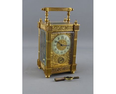 A FRENCH GILT BRASS ALARM CARRIAGE CLOCK having a circular enamel dial and subsidiary alarm dial within a foliate mask, reede