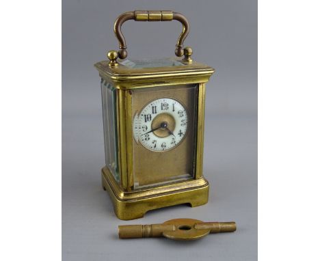 A FRENCH MINIATURE BRASS CASED CARRIAGE CLOCK, the circular enamel dial with Arabic numerals and gilt mask, 9 cms high handle