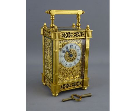 A 19th CENTURY FRENCH GILT BRASS CARRIAGE CLOCK having fluted column sides with cap finials, the sides and mask of pierced fl