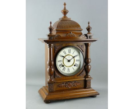 A GERMAN WALNUT CASED MANTEL CLOCK, eight day pendulum driven movement striking on a gong, 53 cms high overall, 31 cms wide