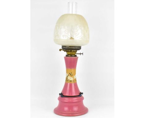 A late 19th/early 20th century oil lamp with pink glazed pottery column and base, with central band of enamelled flowers, wit
