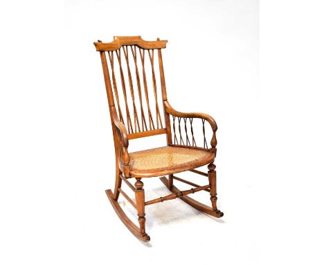 A late 19th early 20th century country-style light oak rocking chair with twist cane back and sides, rattan overlarge seat, u