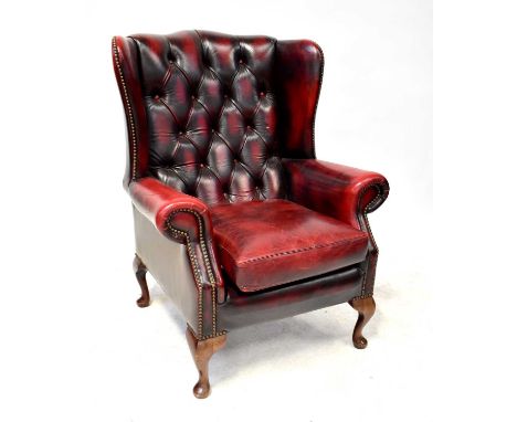 A modern oxblood red leather button wing back armchair.Condition Report: Overall solid but used condition, see additional ima