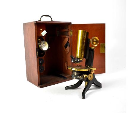 A brass and lacquered monocular microscope with extra lenses and fitments, within a wooden case.