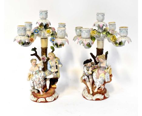 SITZENDORF; a pair of four branch figures candlesticks, with courting couples under rose strewn bowers, height 36cm (2).Condi