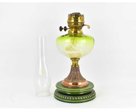 A 19th century oil lamp with green glass font, raised on copper tapered stem with acanthus leaf decoration, on green circular