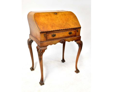 An early 20th century walnut veneered drop-front bureau with curved shaped top, leather inset fall front enclosing a fitted i