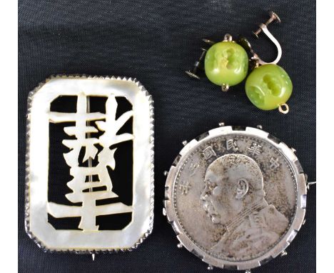 A late 19th century Chinese brooch of lozenge shape, the central mother of pearl inset carved with Chinese script in a white 