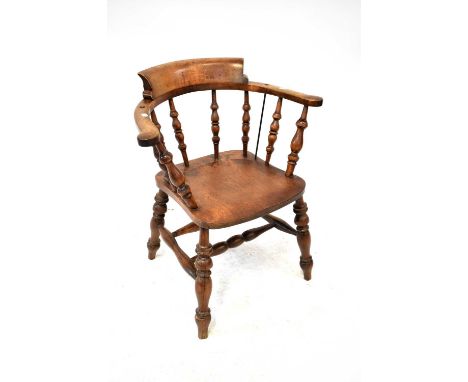 An early 20th century oak captain's chair with turned bobbin seat supports and curved back rails to outswept arms, to turned 